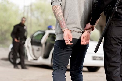 cropped image of policewoman walking with criminal in handcuffs