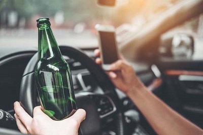 Drunk man driving a car on the road holding bottle beer Dangerou