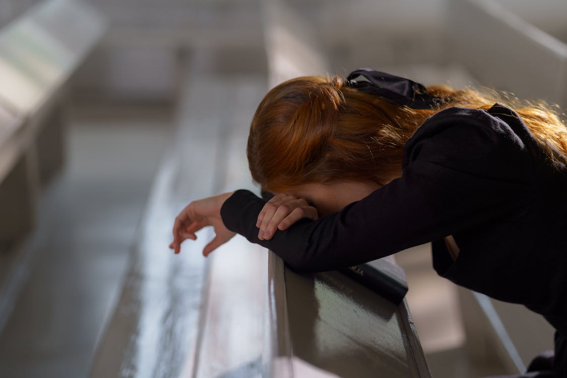 woman with her head down leaning on a bench
